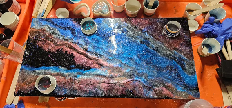A galaxy-coloured resin pour in progress on the work table