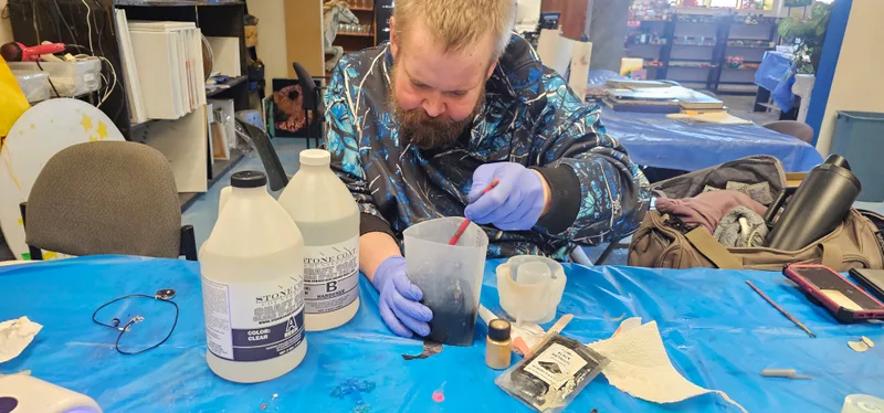 Pouring epoxy, gloved, in the studio